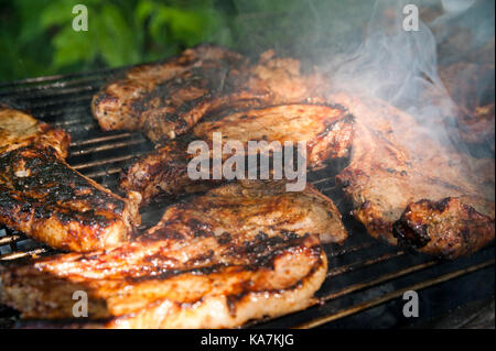 Well cooked delicious brisket steaks on a hot grill with a smoke Stock Photo