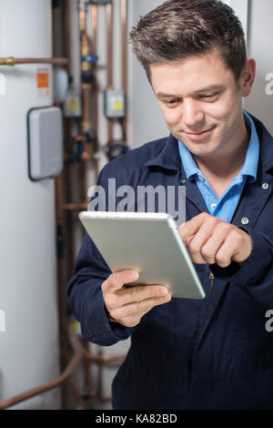 Male Plumber Working On Central Heating Boiler Using Digital Tablet Stock Photo
