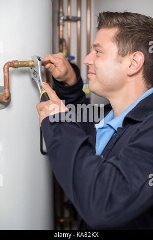 Male Plumber Working On Central Heating Boiler Stock Photo