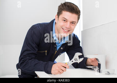 Portrait Of Plumber Working On Sink Using Wrench Stock Photo