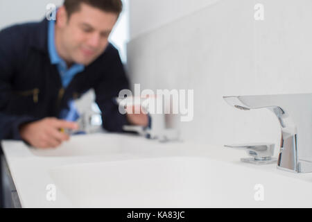 Plumber Working On Sink Using Wrench In Bathroom