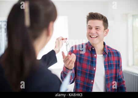 Man Collecting Keys To New Home From Female Realtor Stock Photo