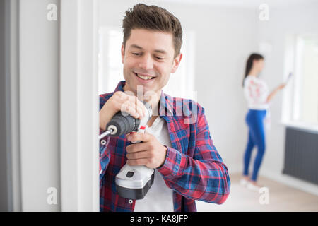Man Using Electric Drill As Couple Renovate Property Together Stock Photo