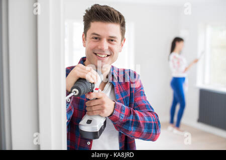Man Using Electric Drill As Couple Renovate Property Together Stock Photo