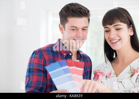 Couple Looking At Paint Swatches In New Home Stock Photo