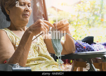 The old woman knits woolen clothes. Close-up of hands knitting. Knitting needles. Stock Photo