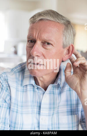 Portrait Of Mature Man Suffering From Deafness At Home Stock Photo