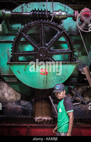 A sugar factory worker with machinery inside Tasikmadu sugar factory in Central Java, Indonesia. Stock Photo