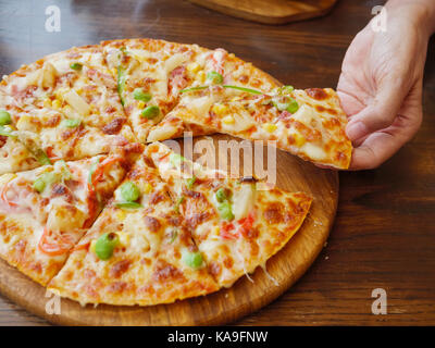 Hands taking slices of italian pizza on wooden board Stock Photo