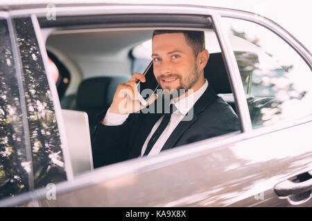 Serious businessman using his phone in his car Stock Photo