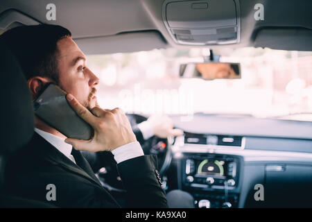 Man using his phone while driving the car Stock Photo