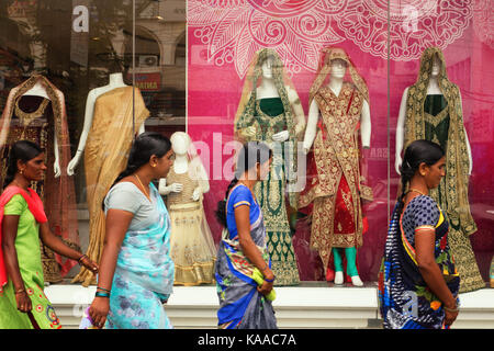HYDERABAD,INDIA-25th SEPTEMBER,2017.Indian women walk past Mannequins draped in traditional ethnic indian wear behind a glass window to attract custom Stock Photo