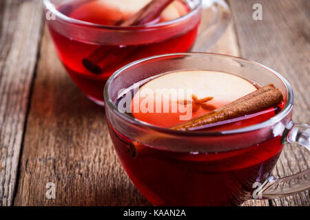 Mulled wine with apple slices in glass mugs on rustic wooden table served for two persons Stock Photo