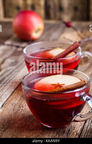 Mulled wine with apple slices in glass mugs on rustic wooden table served for two persons Stock Photo