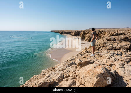 Woman admiring wild beach, coast of Ras Al Jinz, Sultanate of Oman, with copy space perfect for travel concepts and destination backgrounds Stock Photo