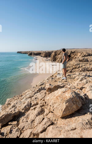 Woman admiring wild beach, coast of Ras Al Jinz, Sultanate of Oman, vertical view perfect for travel concepts and destination backgrounds Stock Photo