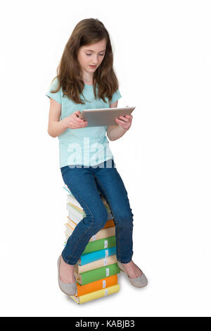 Girl With Digital Tablet Sitting On Multi-colored Stack Of Books Over White Background Stock Photo