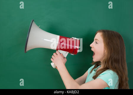 Girl Announcing On Megaphone Against Chalkboard In Classroom Stock Photo