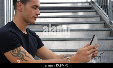Young man watching video on tablet PC outdoor in city Stock Photo