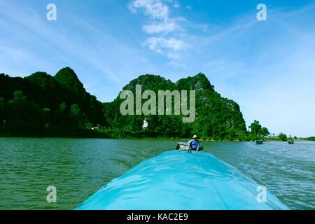 QUANG BINH, VIETNAM - AUGUST 11, 2017: Amazing natural landscape at Quang Binh, Viet Nam on day, boat moving on river, riverside house with mountains  Stock Photo