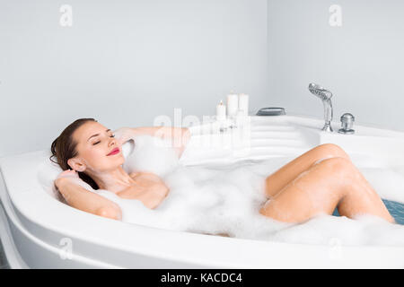 Young beautiful woman enjoying bathing in bathtub