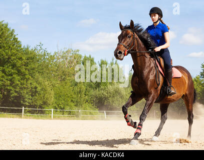 Female jockey galloping on horseback at racetrack Stock Photo