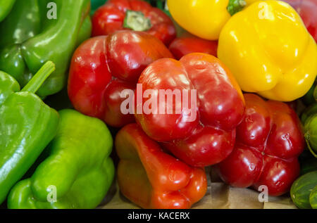 Red, green and yellow bell peppers piled up on a market stall Stock Photo