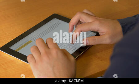 Close-up of male hands using modern digital tablet and computer at office, frontal view of businessman hands typing text information on touch screen of tablet pc Stock Photo