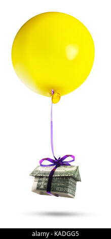 Housing bubble. Isolated origami cash home with a yellow balloon. Stock Photo