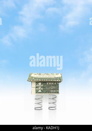 Real estate boom. Origami cash home with a metal coil spring. Stock Photo