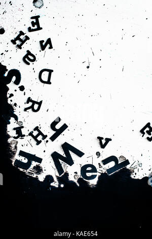 Scattered letters in blurring spilled ink. Creative writing concept. High contrast still life with creative writer workplace. Copy space. Stock Photo