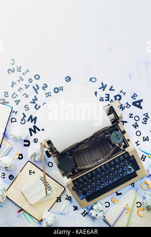 Writer workplace with scattered letters, stationery and a typewriter. Crumpled paper balls with pencils on a white wooden background, creative writing
