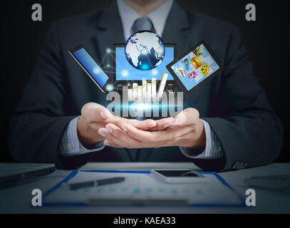 Businessman present increasing graph on hand with LCD screen, tablet, globe, business growth Stock Photo