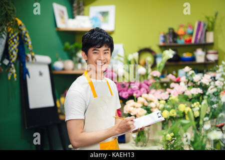 Busy florist drawing something in notepapd at workplace Stock Photo