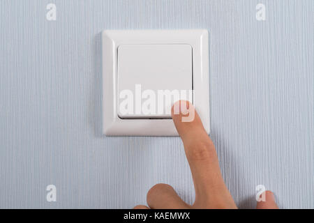 Close-up Of Hand Pressing White Switch On Wall Stock Photo