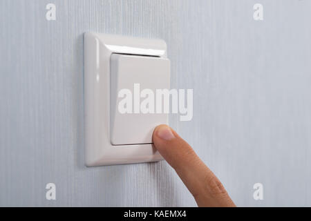 Close-up Of Hand Pressing White Switch On Wall Stock Photo