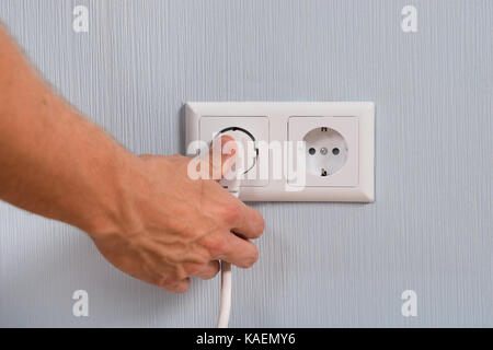 Closeup Of Hand Inserting An Electrical Plug Into A Wall Socket Stock Photo