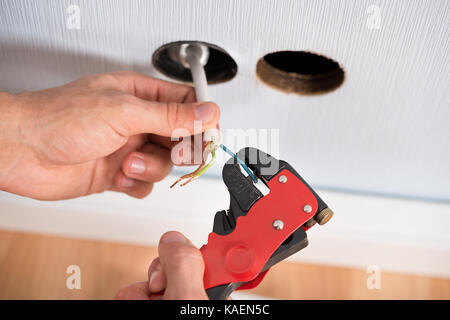 Closeup Of Electrician Hands Stripping Electrical Wires For Wall Socket Stock Photo