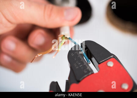 Closeup Of Electrician Hands Stripping Electrical Wires For Wall Socket Stock Photo