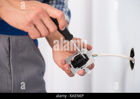 Close-up Of Electrician Hands Installing Wall Socket Stock Photo