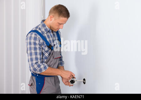 Young Electrician Installing Electrical Socket On Wall In House Stock Photo