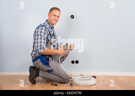 Young Electrician Stripping Wire With Plier In House Stock Photo