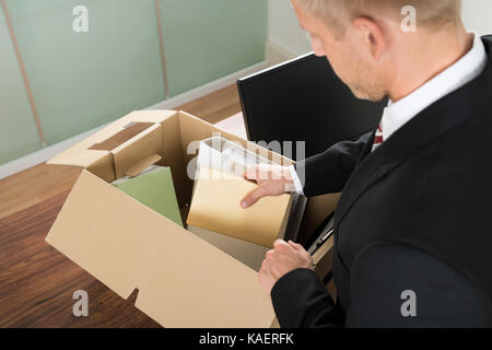 Close-up Of A Businessman Packing Files In Cardboard Box At Office Stock Photo
