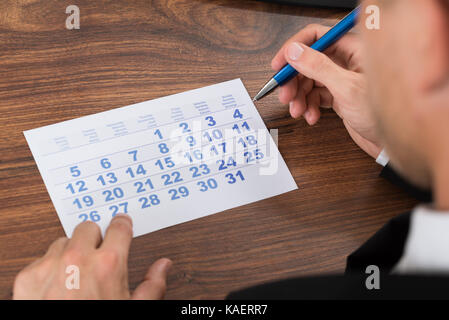 Close-up Of Man Marking With Pen And Looking At Date On Calendar Stock Photo