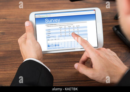 Close-up Of Businessperson Hand Pointing On Mobile Phone Showing Survey Form Stock Photo