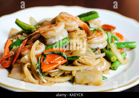 Pad Khee Mao, Stir-fried with wide rice noodles, hot peppers, carrots, green beans, onions, tomato and sweet basil leaves. Stock Photo
