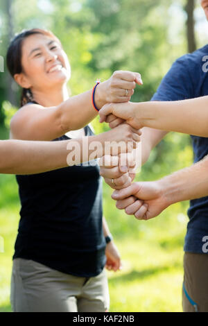 Coworkers Stacking Fists In Forest Stock Photo