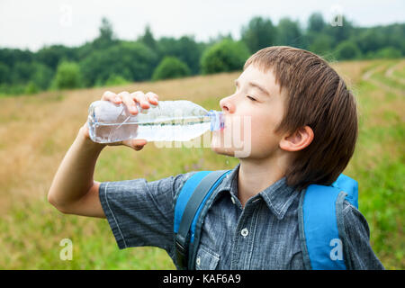 Boy drinking water from pet bottle outdoors Stock Photo