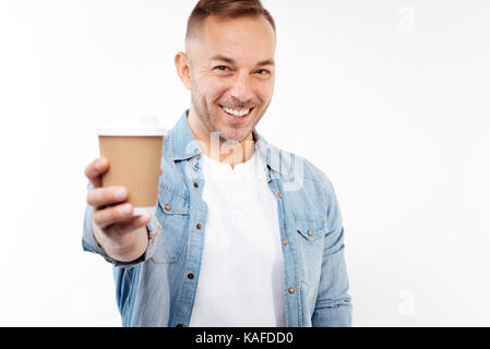 Pleasant smiling man handing a cup of coffee Stock Photo