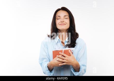 Happy young woman pressing gift box to her chest Stock Photo